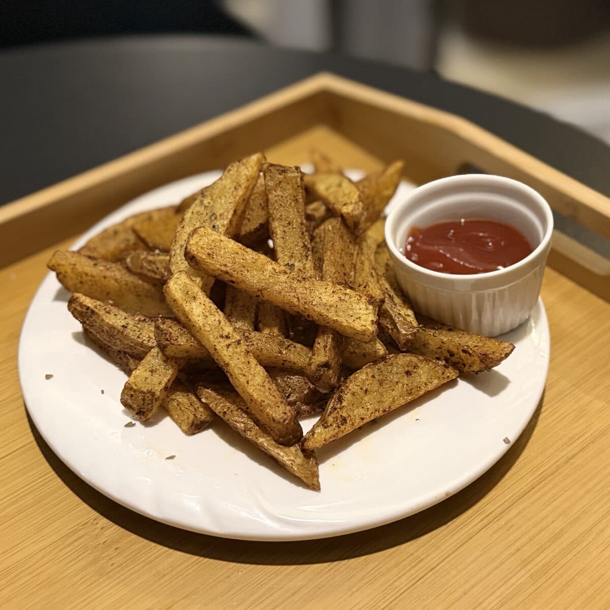 A plate of seasoned fries with a dip